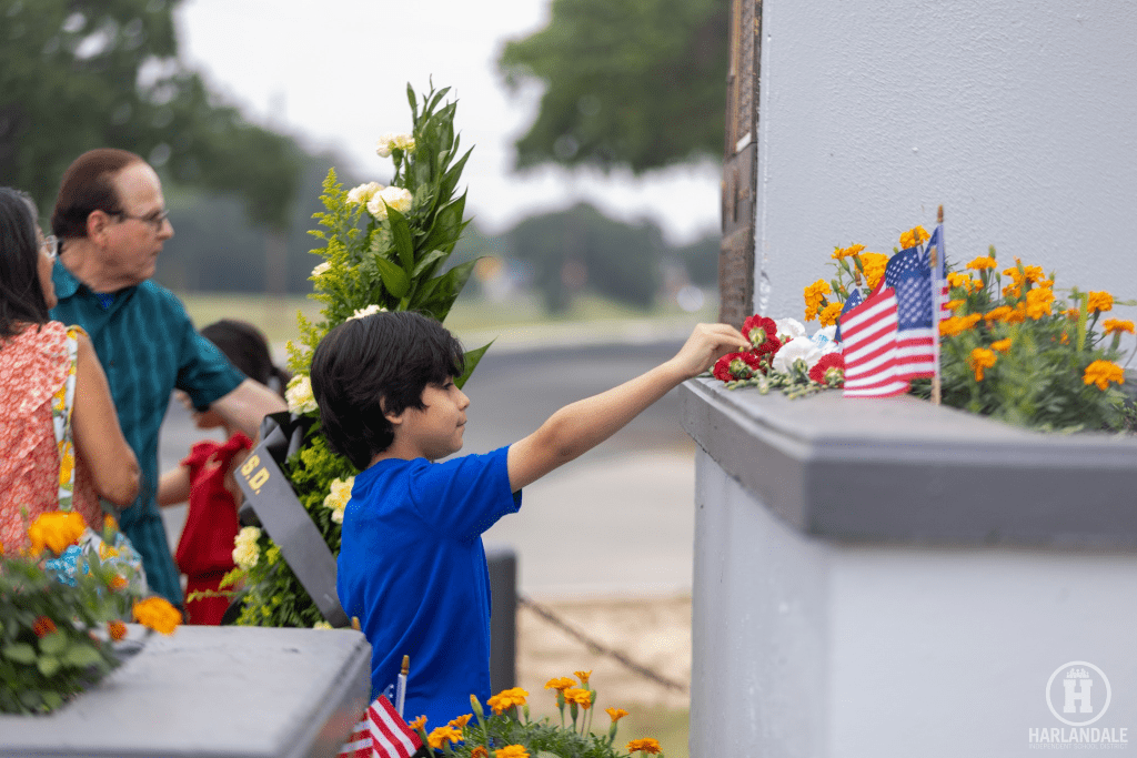 Harlandale ISD student putting a flag on the memorial