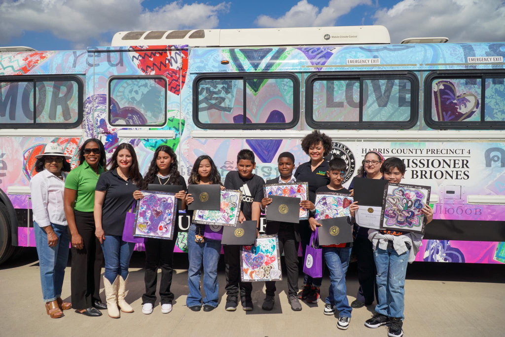 students stand in front of bus with their art